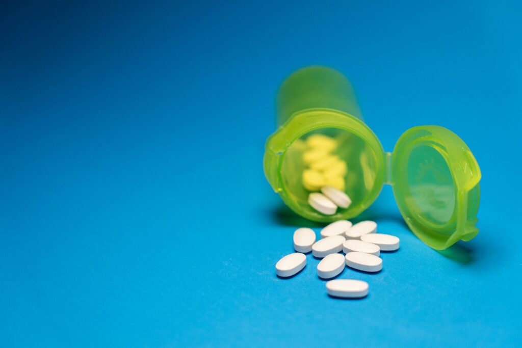 Open Pill Bottle with White Tablets on Blue Background